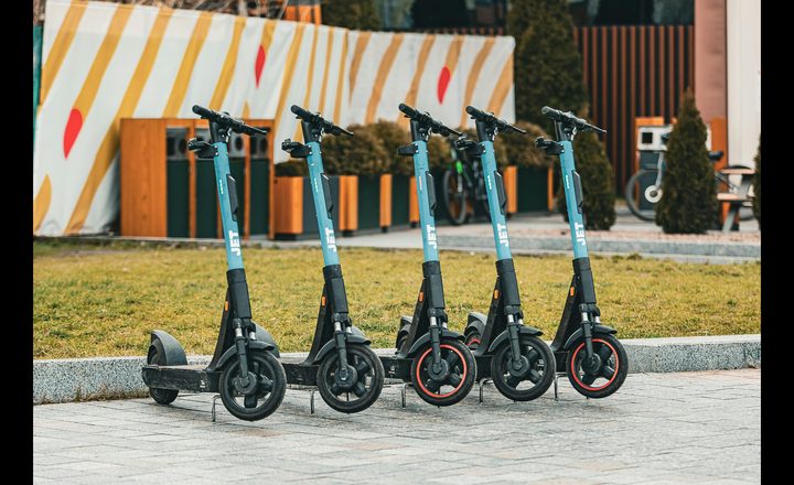 Cinco patinetes eléctricos azules alineados en una plaza urbana